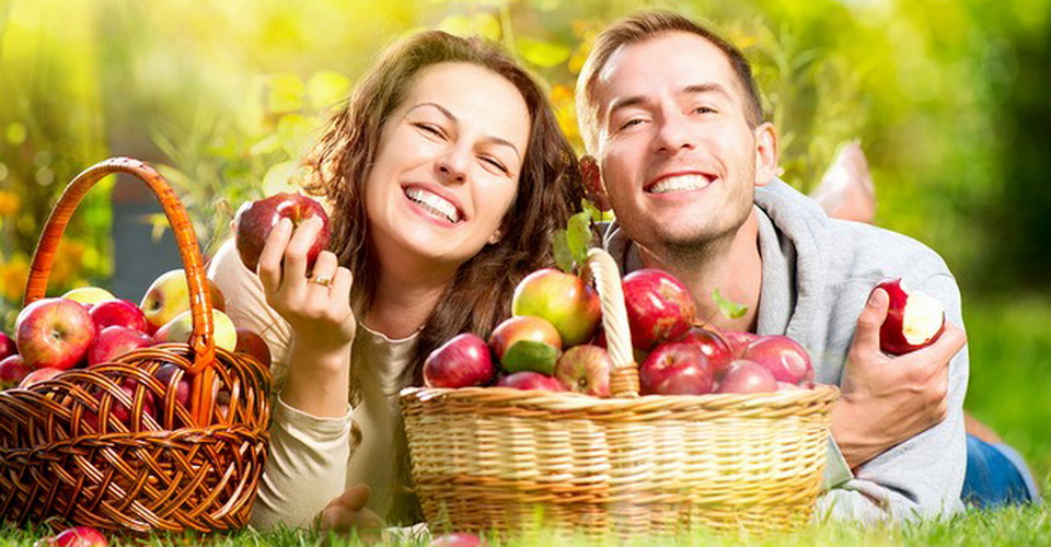 Happy People Eating Organic Apples in Autumn Garden.Healthy Food